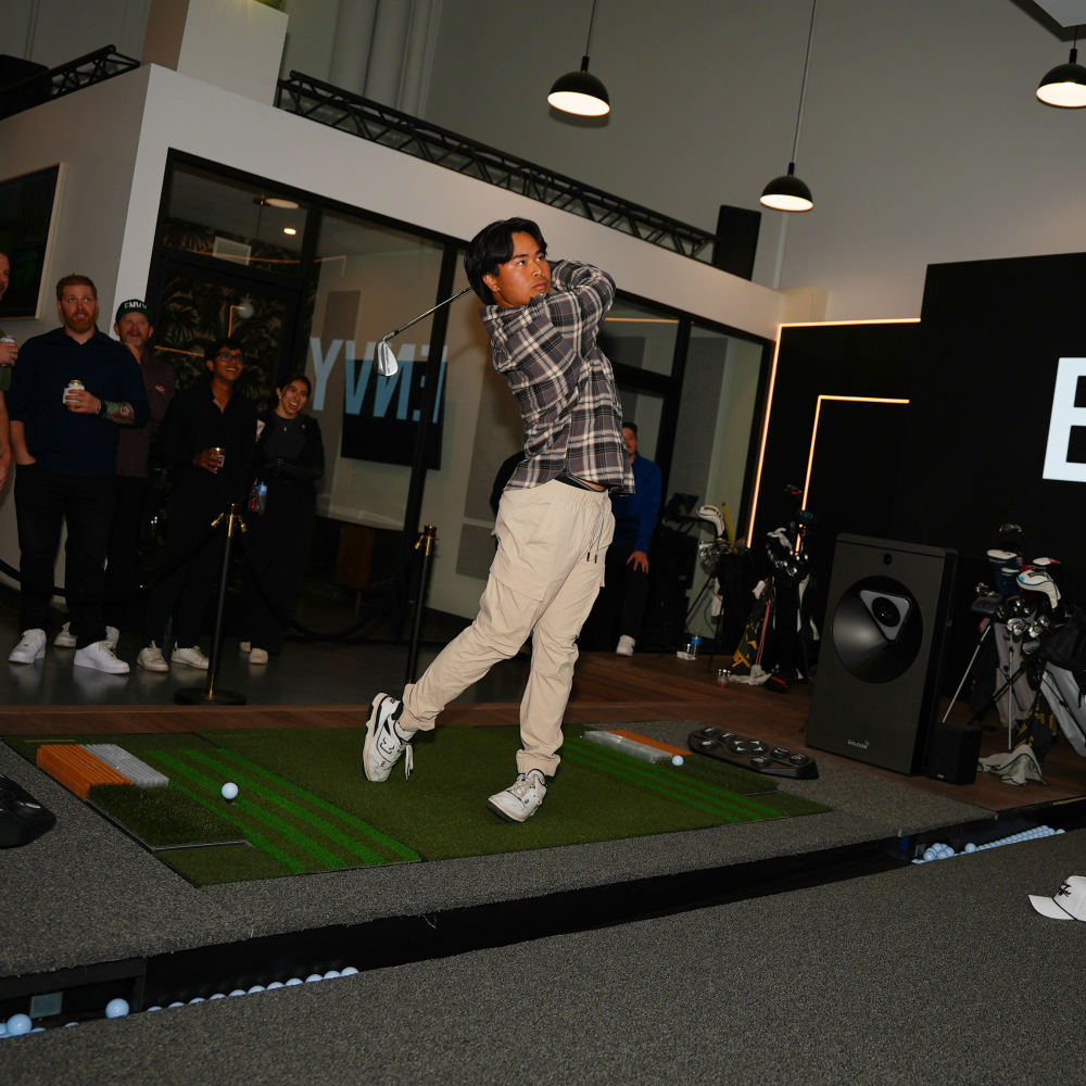 Young man swinging a golf club on the GOLFZON TwoVision Simulator