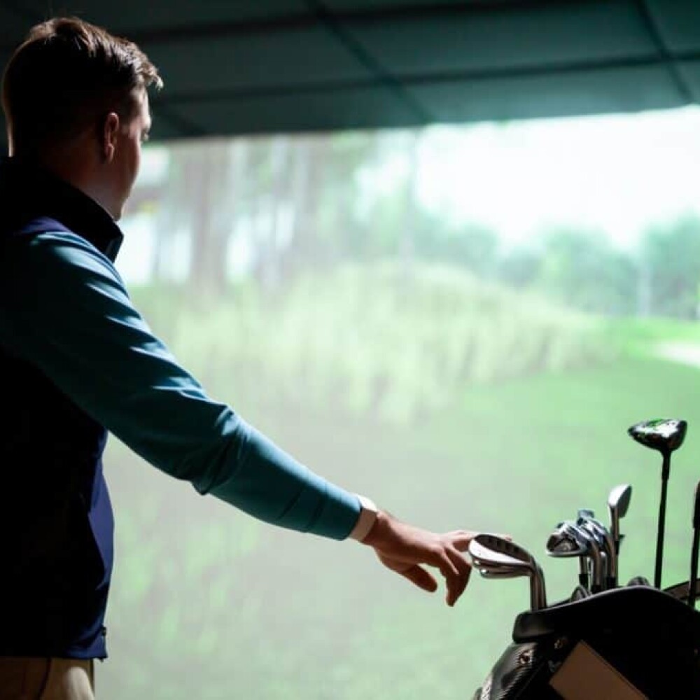 Golfer Looking At Screen With Hand on Golf Clubs in Golf Bag