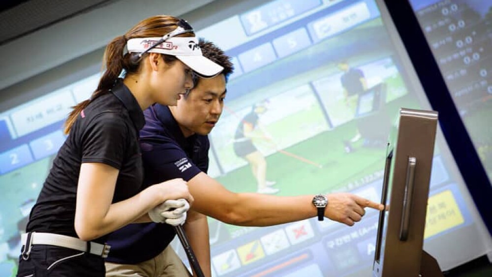 David Leadbetter Golf Academy Instructor Showing Metrics to Female Golfer on Golfzon Golf Simulator