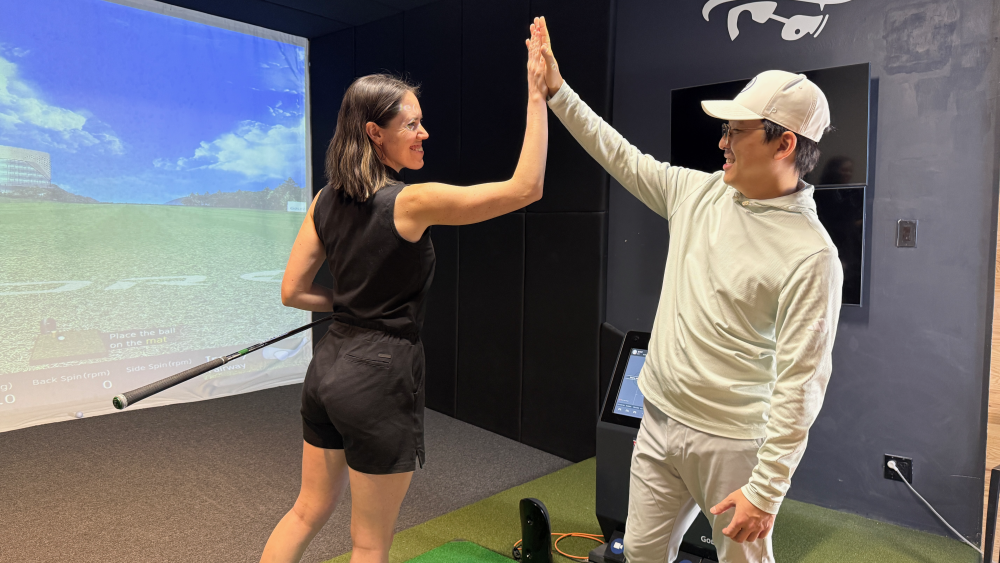 Golfzon Range Instructor giving a high five to female student after a great shot.
