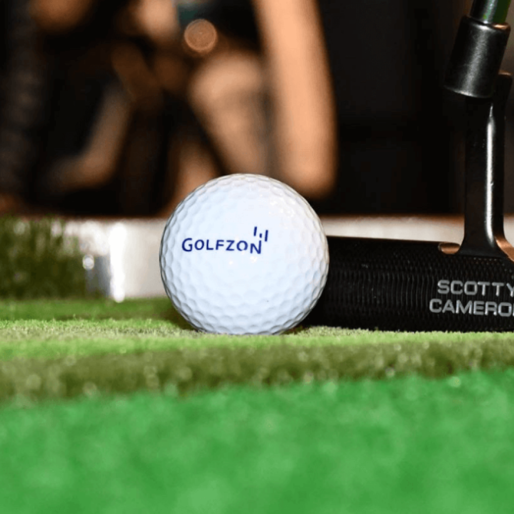 Golfzon Golf Ball with Scotty Cameron Putter Behind On Fairway Mat