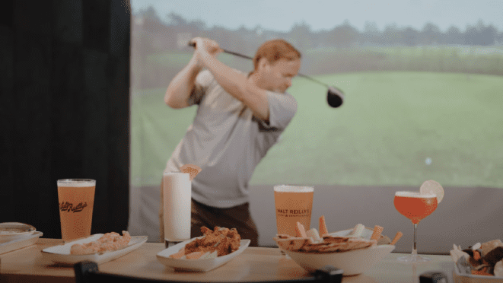 Walt Reillys Food and Drink Foreground, Golfer on Golfzon Golf Simulator Blurred in Background TwoVision Vision