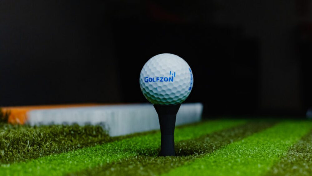 Golfzon Golf Ball on Auto Tee with Multi-Material Lies in Background