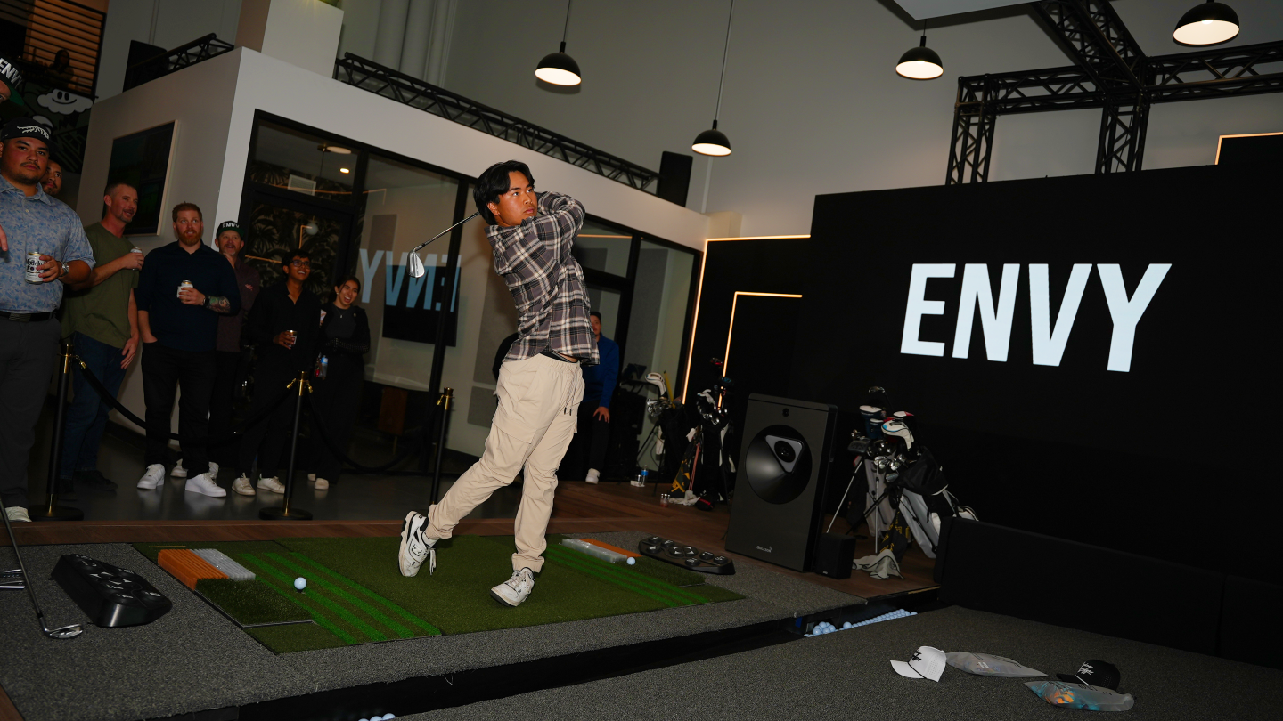 Young man swinging a golf club on the GOLFZON TwoVision Simulator