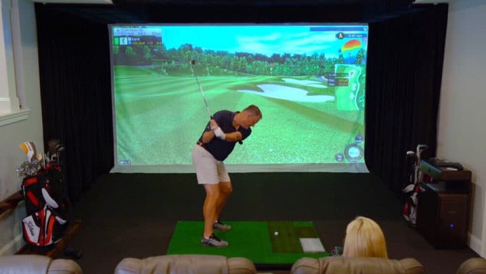 Male Golfer Swinging on Golfzon Residential Home Simulator Golfzon, Spectator in Theatre Seat Behind